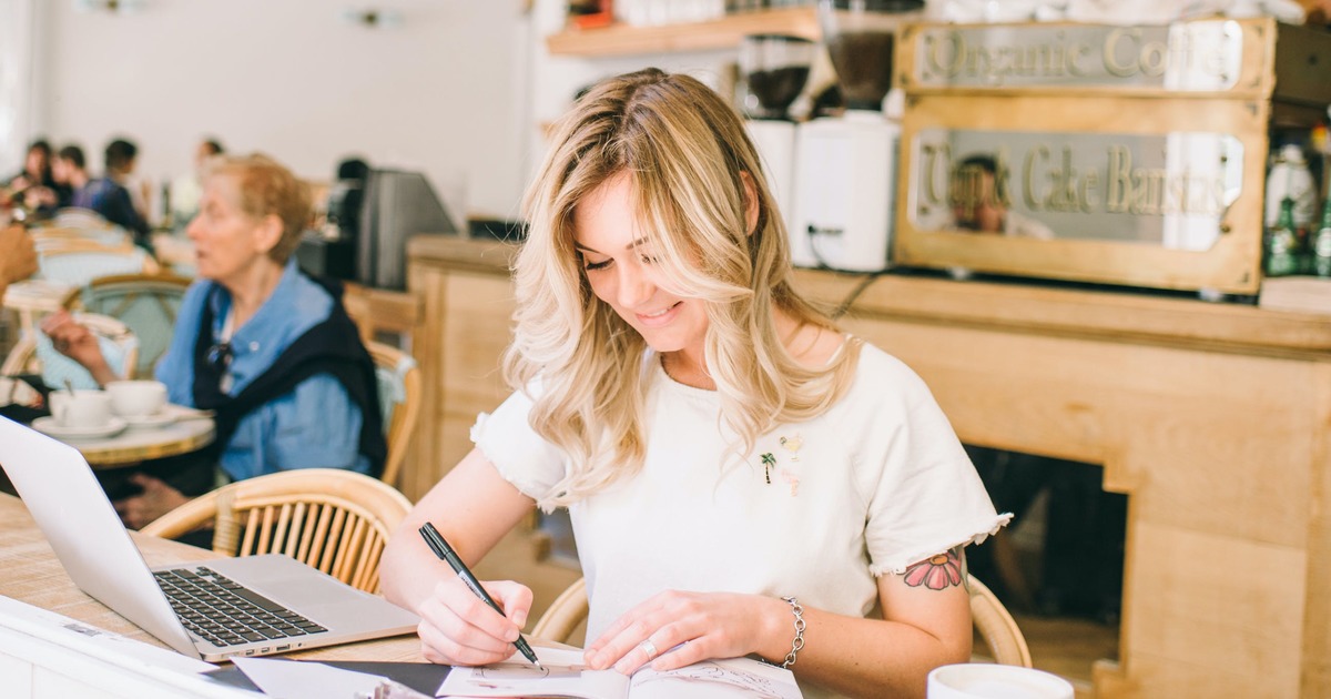 Writer at coffee shop typing on a laptop
