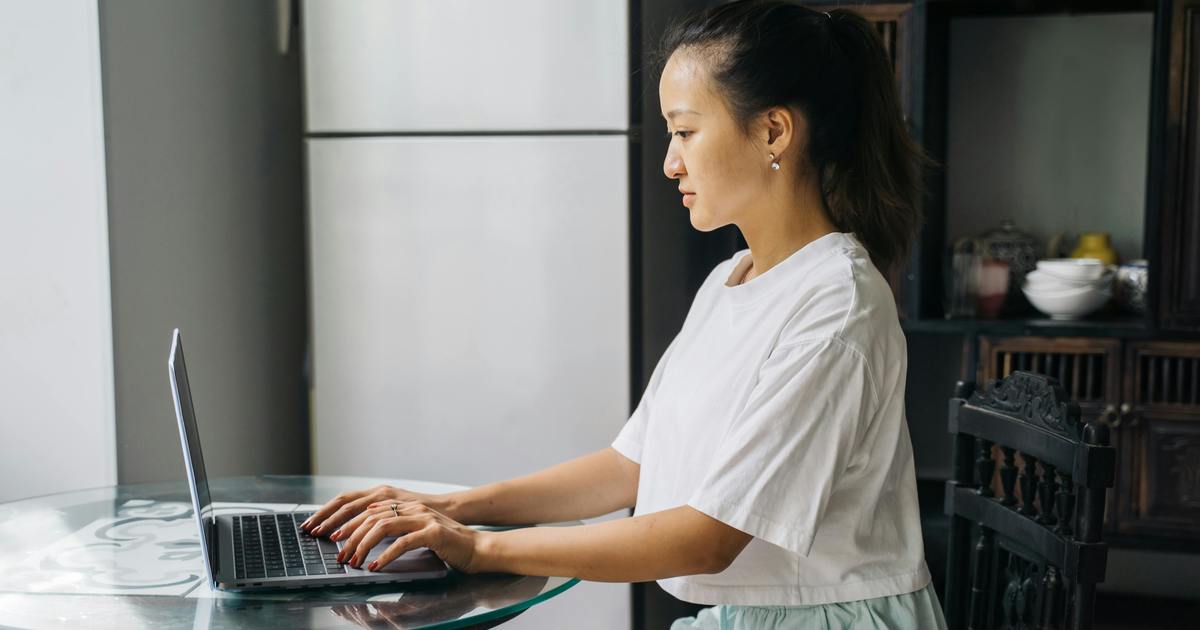 Writer sitting at table typing on laptop