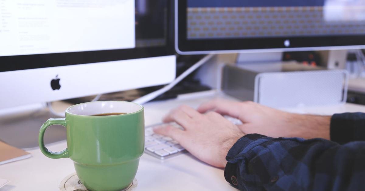 Writer typing on a laptop with coffee cup
