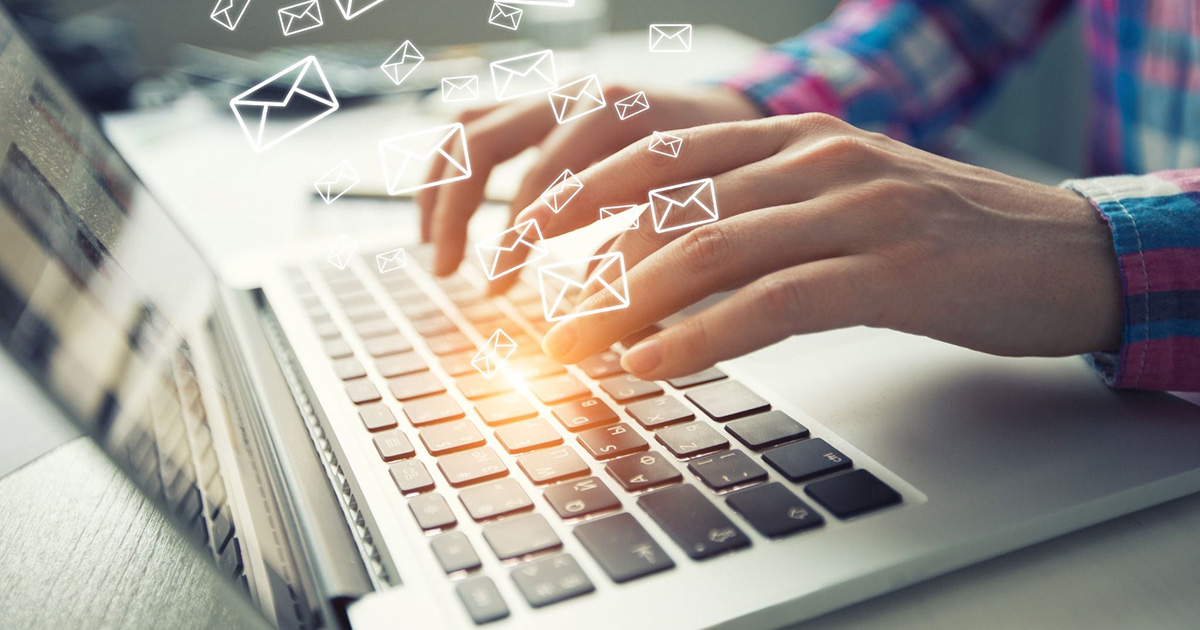 Photo of a person typing on a laptop with email graphics rising from the keyboard.